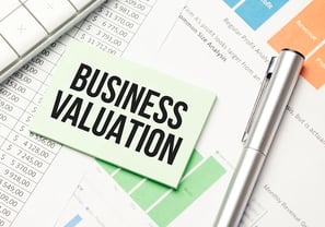 Hand holding a scale balancing coins and a business model.