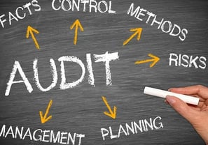 Magnifying glass over financial statements for auditing compliance.