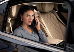 Business woman sat in the rear of a chauffeur car answering her mobile phone