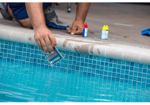 Image of a pool tech kneeling poolside performing a water test