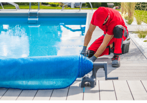 Image of a pool tech preparing a pool closing by rolling out the pool cover