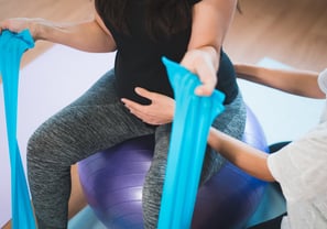 a pregnant woman is sitting on a yoga ball