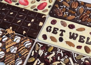 Custom Handcrafted gourmet chocolate bars topped with dried fruits and nuts, elegantly arranged for gifting or indulgence.