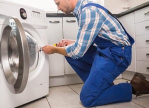a man in overalls and overalls is fixing a washing machine
