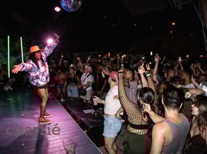 black rapper on stage, arms outstretched while audience close to stage claps with arms raised