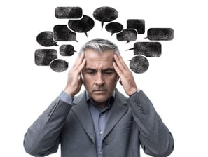 un homme e tenant la tete avec des pensées et un dialogue interieur negatif sous forme de bulle noir