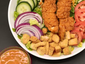 salad in a bowl with a side of dressing