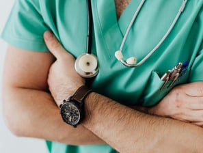 a man in a green scrubsuit with a stethoscope attached to his