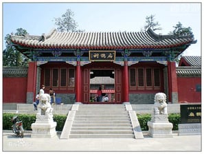 a chinese temple with a large red building and a few statues