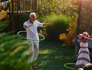 Grandad and his little granddaughter doing hula hooping in the garden