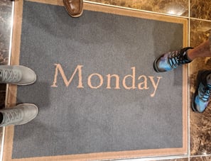 Feet on a rug that says "Monday"