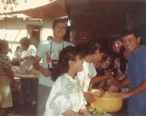 Teenage Aaron Alvarez holding his first camera, smiling with friends in a candid moment.