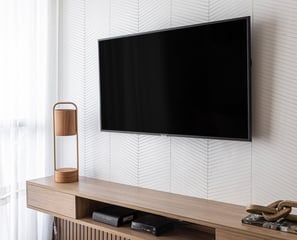 Painel ripado e mobiliário planejado em madeira, trazendo aconchego e elegância para a sala de TV.