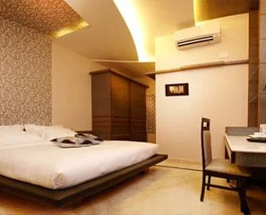 Modern hotel room with a smart TV, desk, and coffee table.