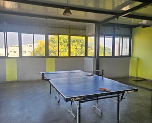 Table tennis area with a table, net, and surrounding floor space.