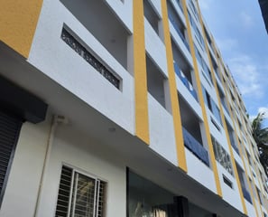 Tall Yellow and white building with lots of rooms and balconys.