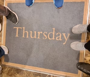 Feet around a rug that says "Thursday"