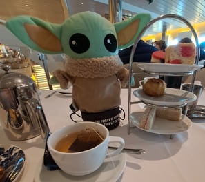 Little Green stuffed Animal on table with Tea cup and cakes