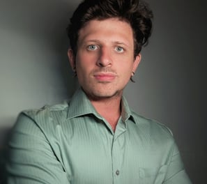 a white man with earrings wearing a green shirt