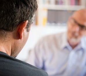 a man in a blue shirt is looking at a cell phone