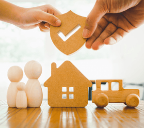 a person holding a piece of wood with a house in the background