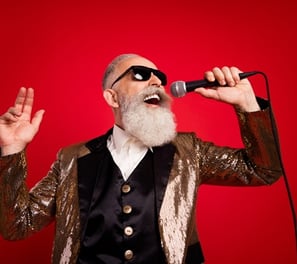 a older man with a beard and sunglasses on a red background