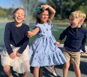 three children playing with a fountain in a park