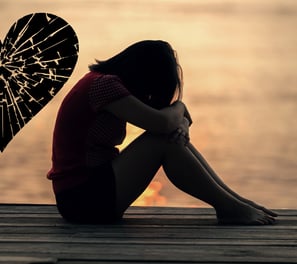 a woman sitting on a dock with a broken heart