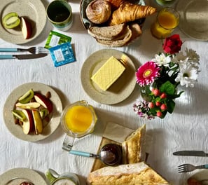 Brunch gourmand avec viennoiseries, fruits frais et fleurs, servi dans une location de charme