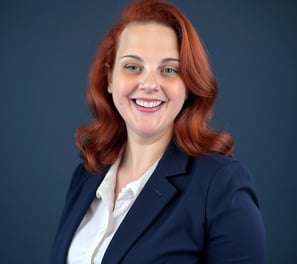 A smiling red haired white woman in a blue blazer