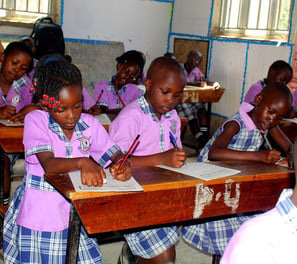 a group of children in school uniforms sitting at desks