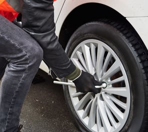 a person standing on a tire with a wrenet