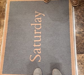 Two pairs of shoes around rug that says "Saturday"