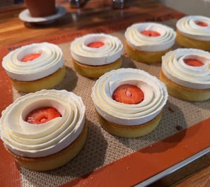 a tray of cupcakes with strawberries and cream