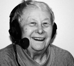 Eine lachende alte Erzählerin unter Headsets