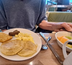 A plate of breakfast foods, potato patty, eggs, pancakes