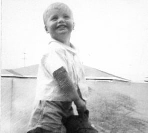 Childhood black & white photo of Cam Beard. founder of Carrots by Cam, riding a hobby horse