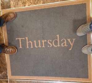 two pairs of shoes around a rug a that says "Thursday"