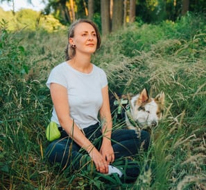 Toni sitzt mit Hund im Wald und blickt ruhig in die Ferne – Stille und Verbindung im Waldbaden