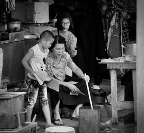 Asian family with roadside stall stirring the ashes in a tin