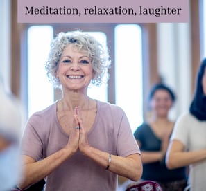 Lady in yoga pose smiling in a class