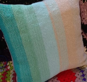 a tunisian crochet pillow with a colorful blanket