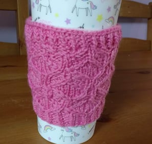 a cup of coffee with a pink cup cosy
