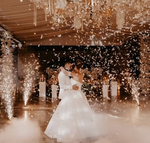 Novios bailando el vals el día de su boda rodeados de mariposas de papel y pirotecnia fria muy feliz