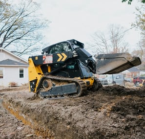 Miniexcavadora realizando trabajos de excavación y traslado de materiales para una obra.