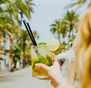 Cóctel mojito refrescante en la terraza de Santa Lola Badalona con palmeras de fondo.