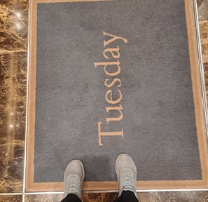 a pair of shoes on a rug that says "Tuesday"