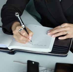 a woman in a suit writing on a notebook