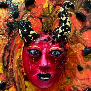 Un visage sculptée rouge avec des cornes dont une cassée