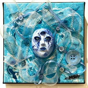 une sculpture d'un visage bleu avec trois yeux et du tissu autour
